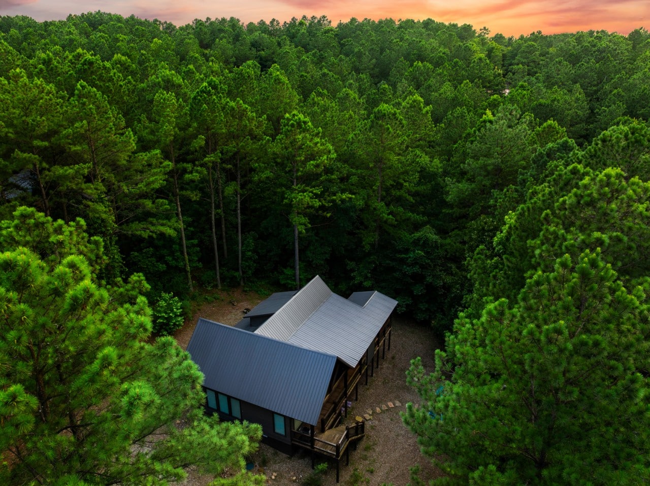 Overhead exterior view with the metal roof and wooded setting.