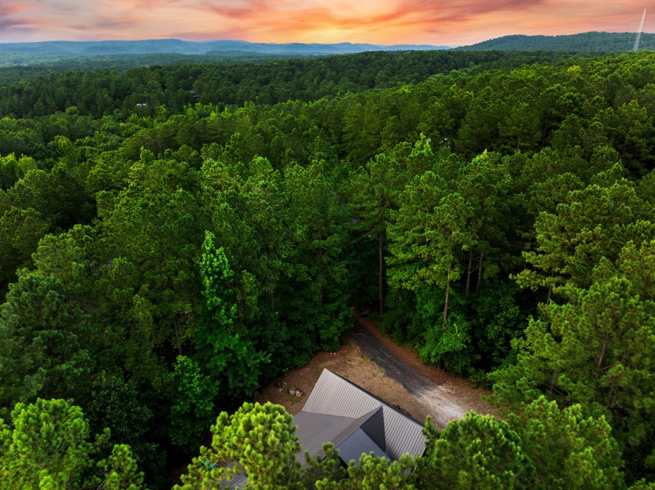 Aerial view of Luna Ridge surrounded by dense forest and sunset sky.