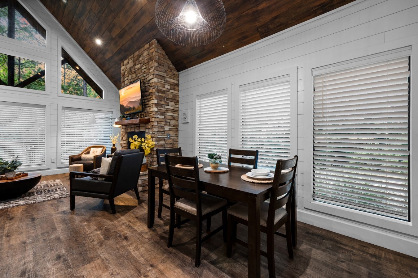 Dining table set beside large windows and the fireplace.