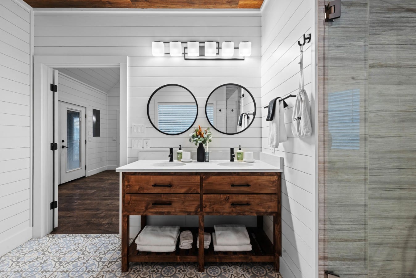 Bathroom vanity with two mirrors and warm wood cabinetry.