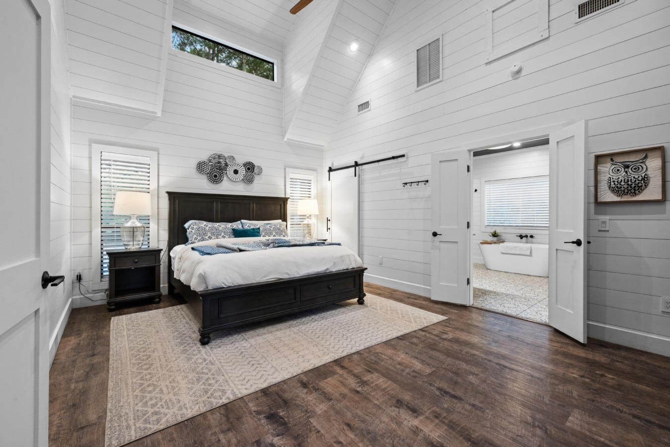 King bedroom with vaulted ceiling, soft lighting, and cabin style.