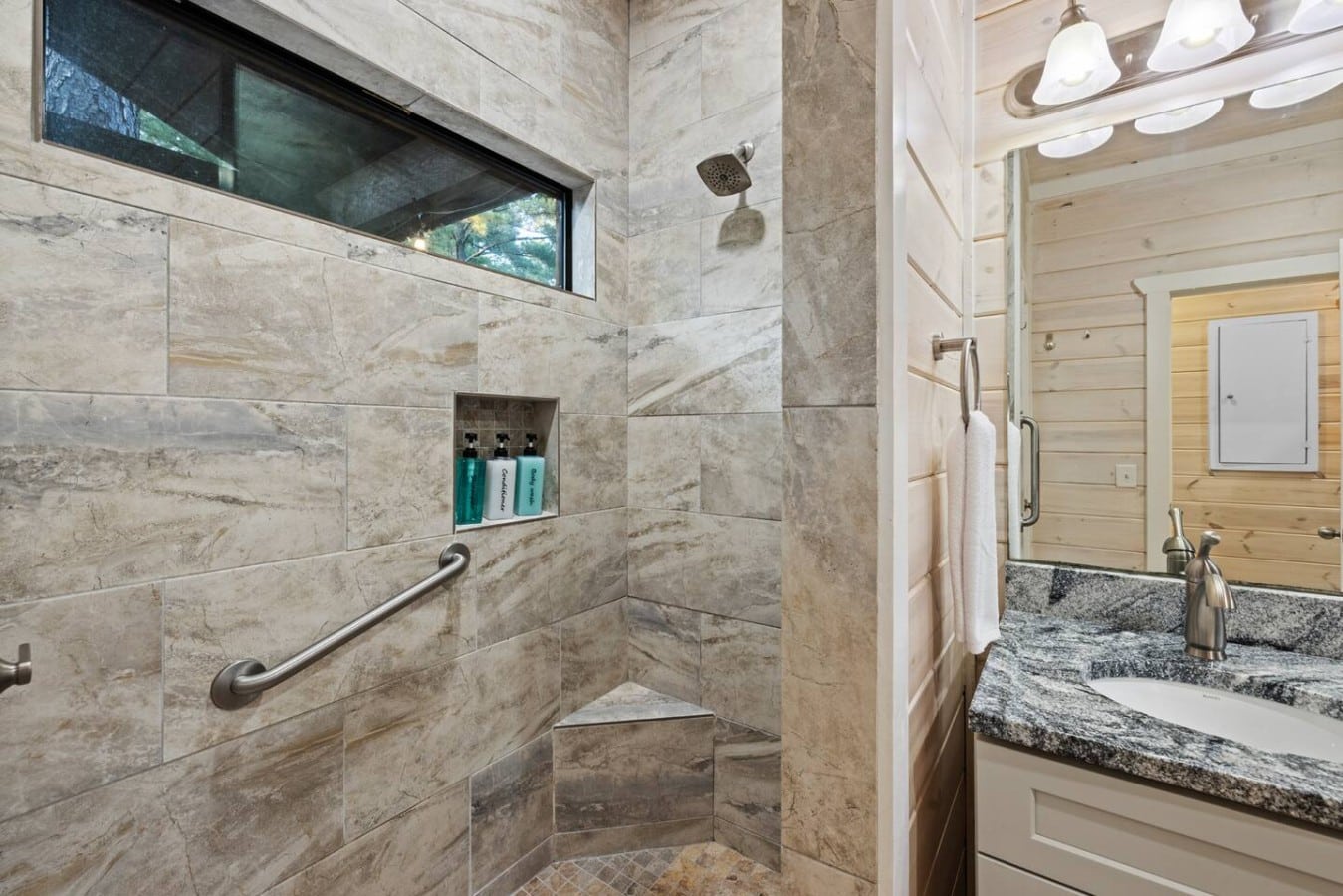 Walk-in shower with built-in bench and modern black fixtures.