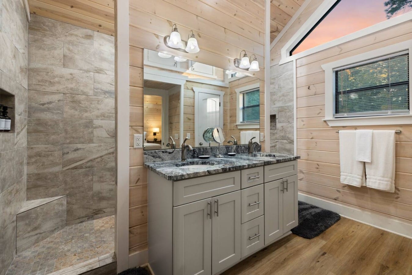 Bathroom vanity and shower entry with coordinated tile finishes.