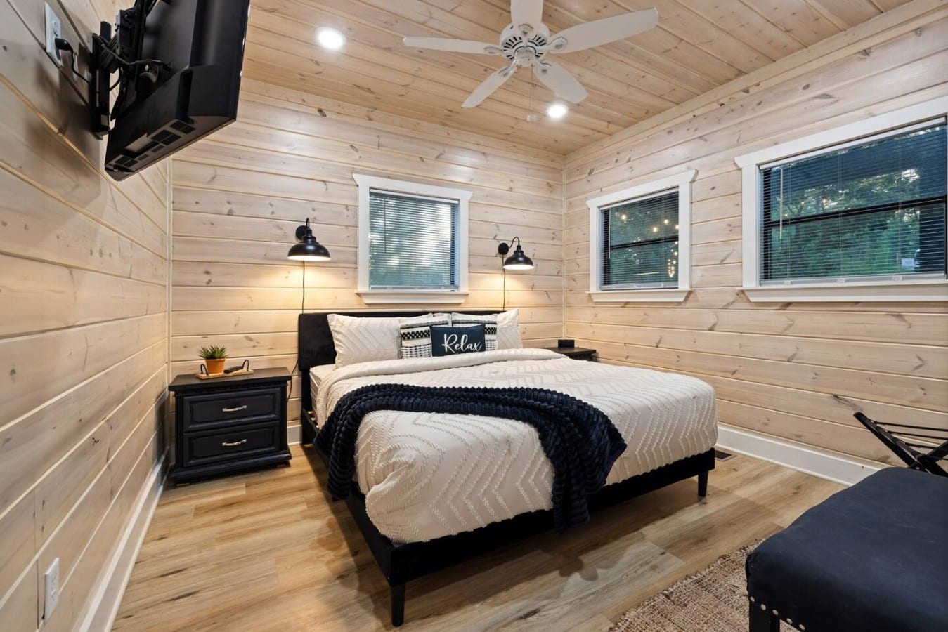 Bedroom angle showing TV, ceiling fan, and bright window light.