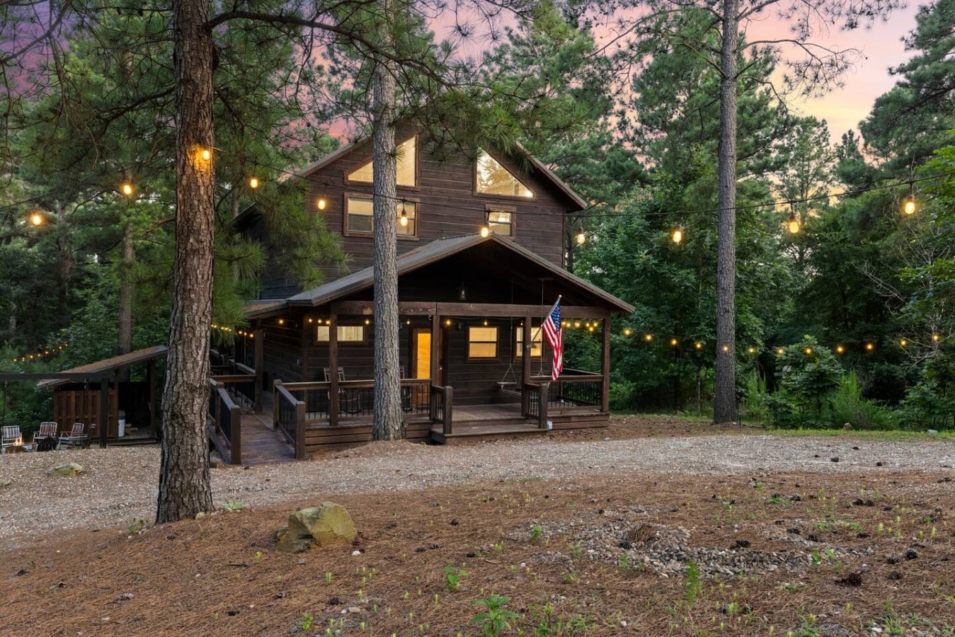 Ground-level exterior view of the cabin and wooded front yard.