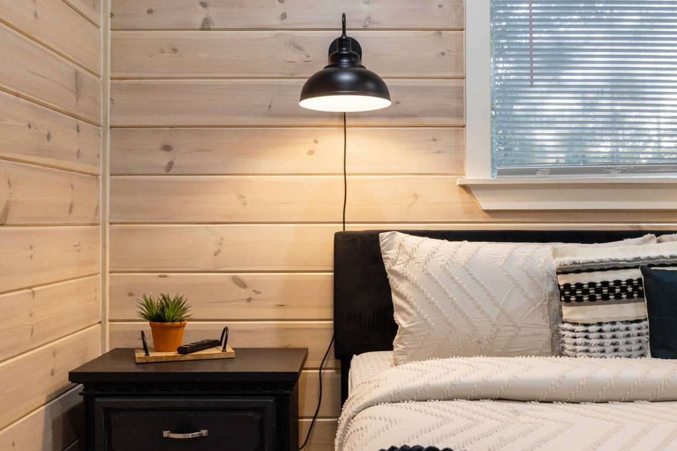 Bedroom detail with nightstand, lamp, and relaxed cabin styling.