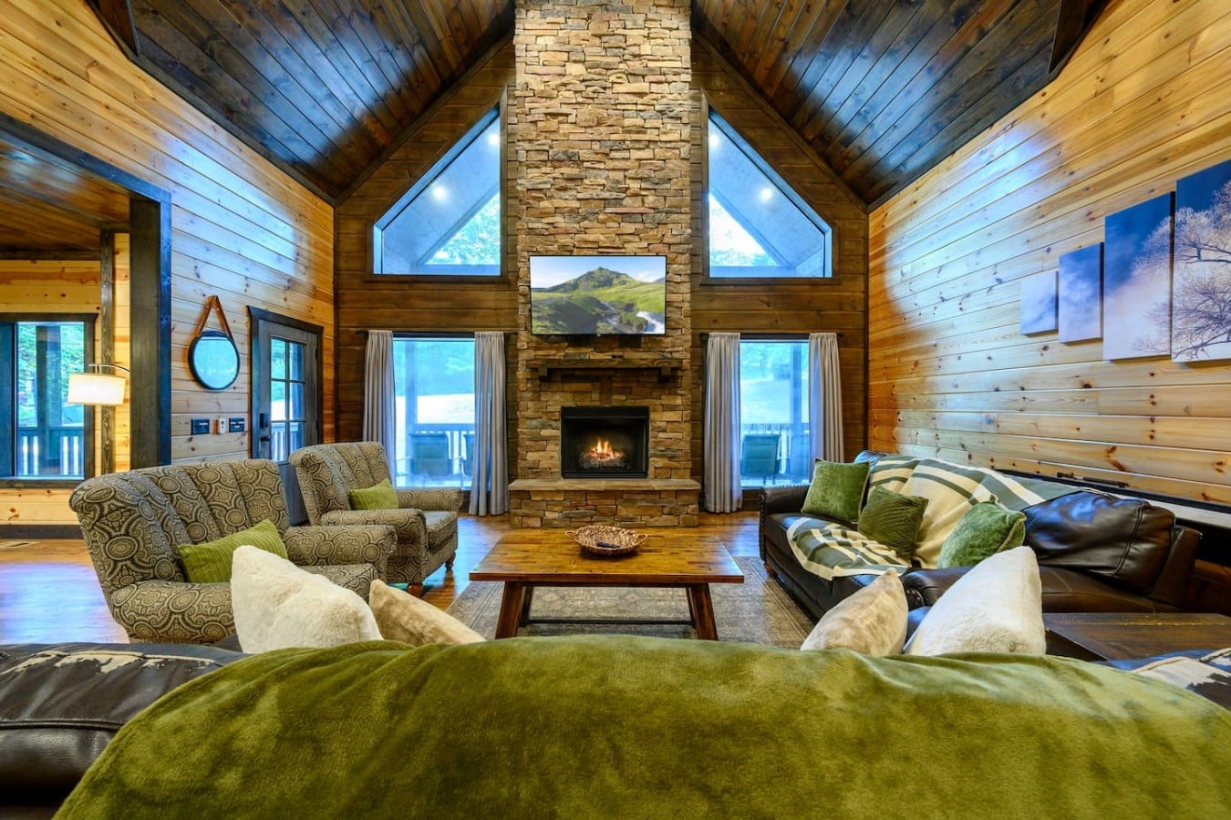 Soaring great room with a stone fireplace, window wall, and comfortable seating.