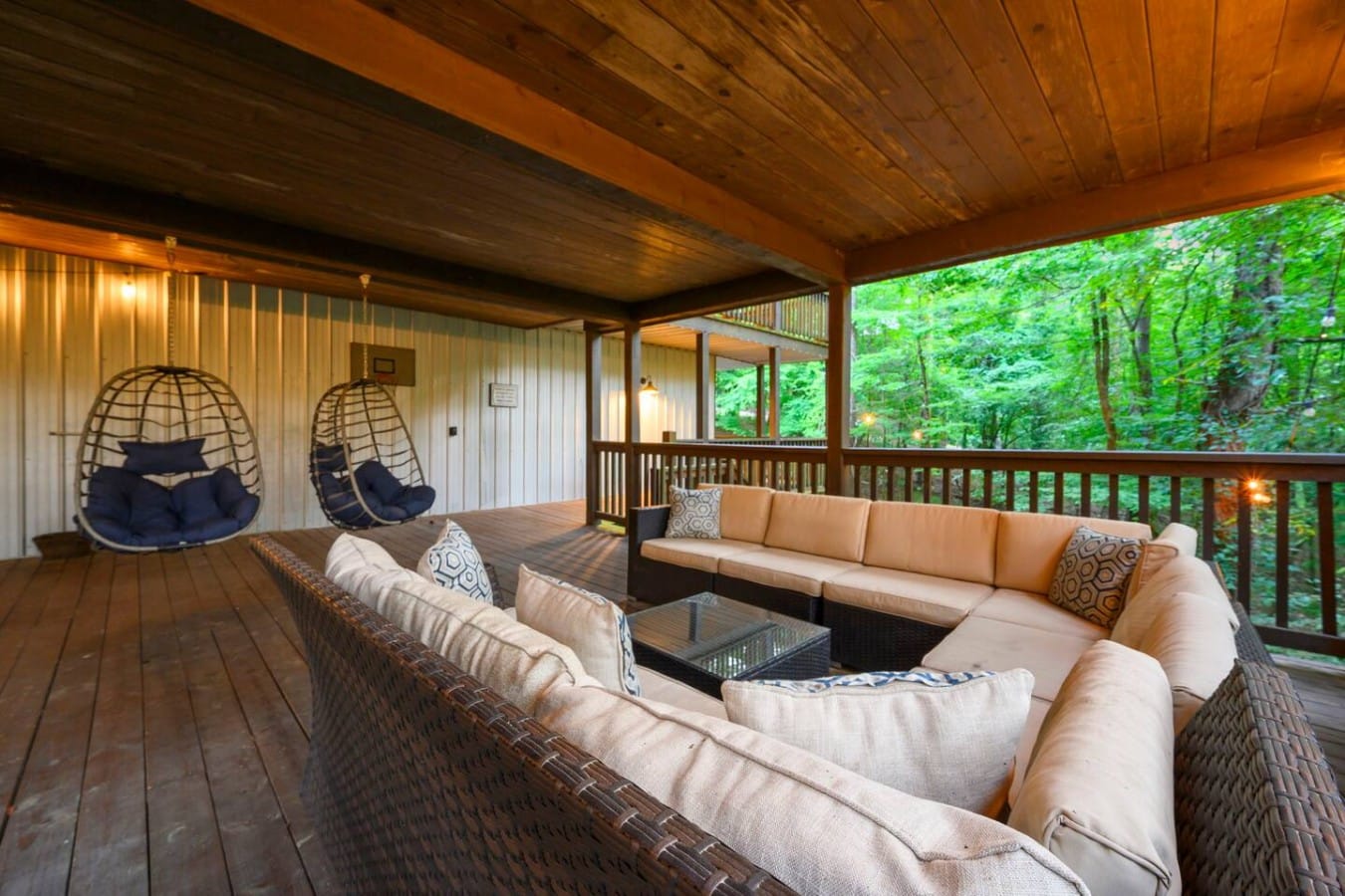 Covered deck lounge with hanging egg chairs and wooded views.