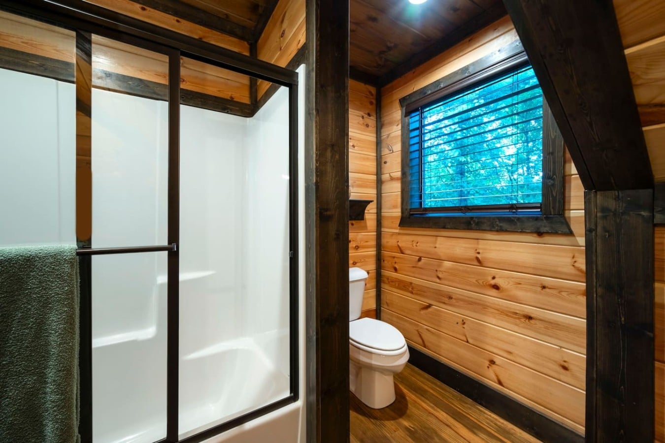 Bathroom with shower, window, and toilet tucked beside the bedroom.