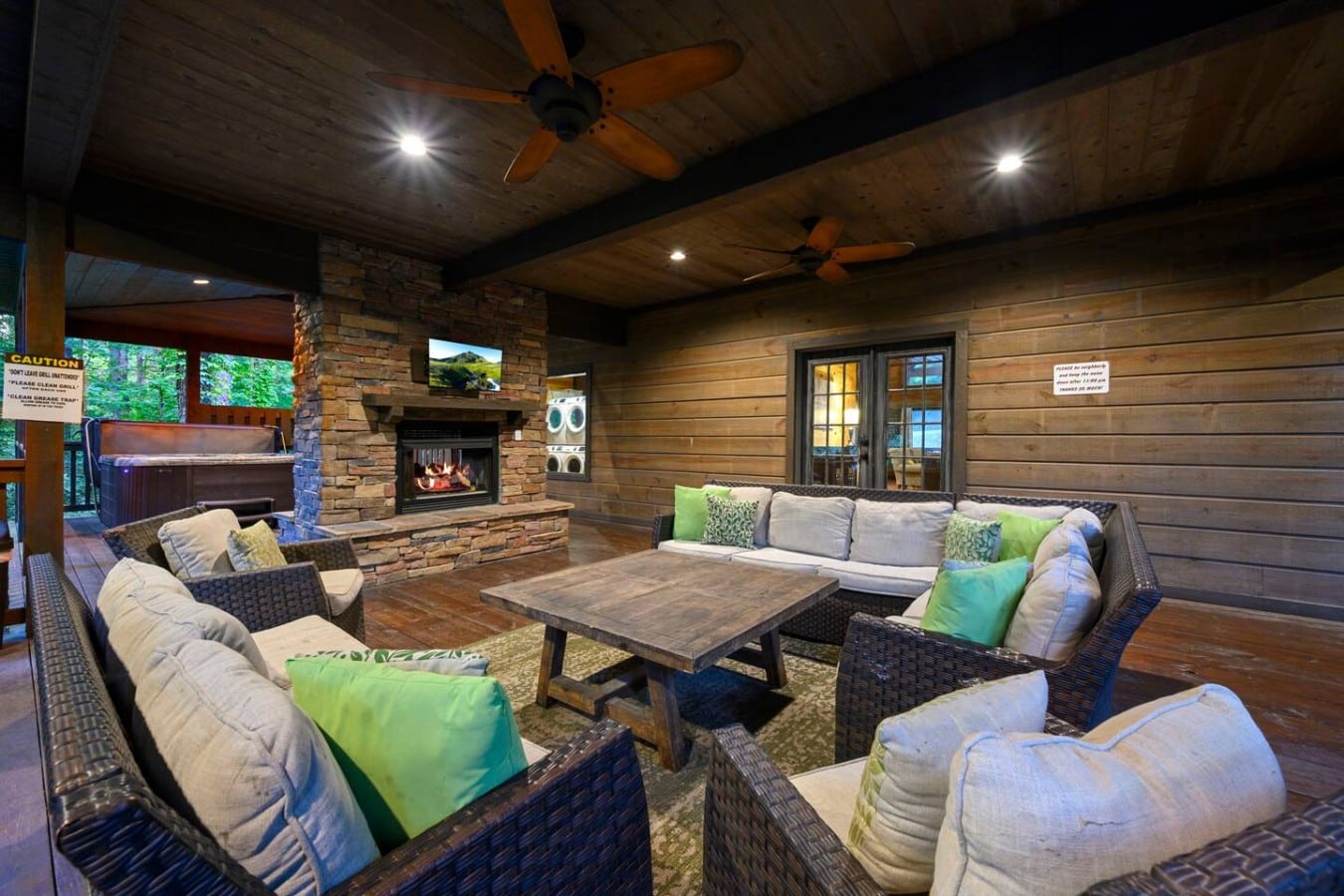 Covered outdoor lounge with sectional seating and fireplace.