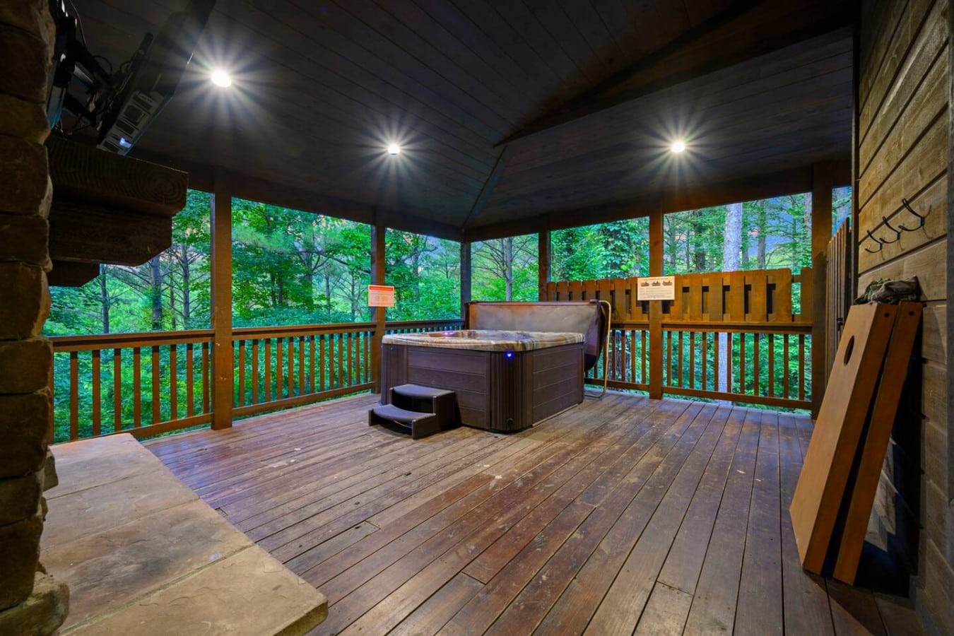 Covered deck with hot tub access and wooded views.