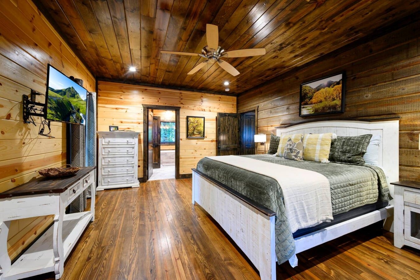 King bedroom with warm wood finishes, TV, and direct deck access.