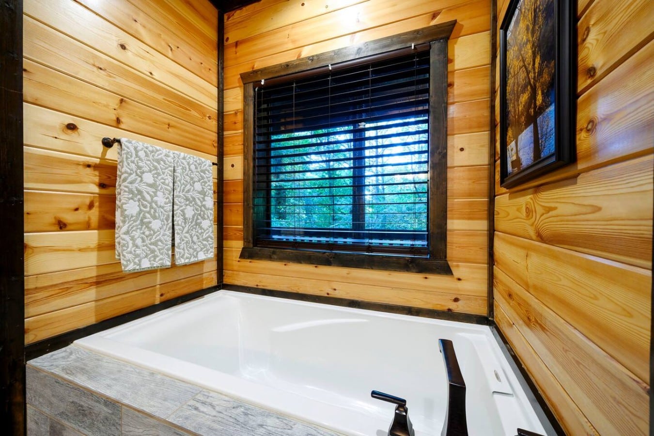 Soaking tub set beside a wooded window for a quiet retreat.