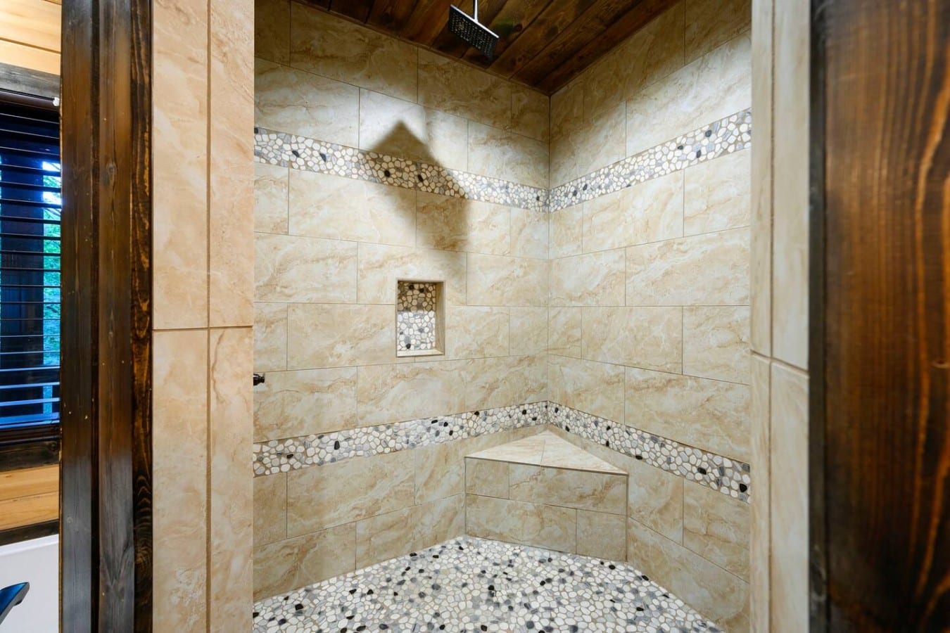 Walk-in tiled shower with built-in bench and decorative tile.