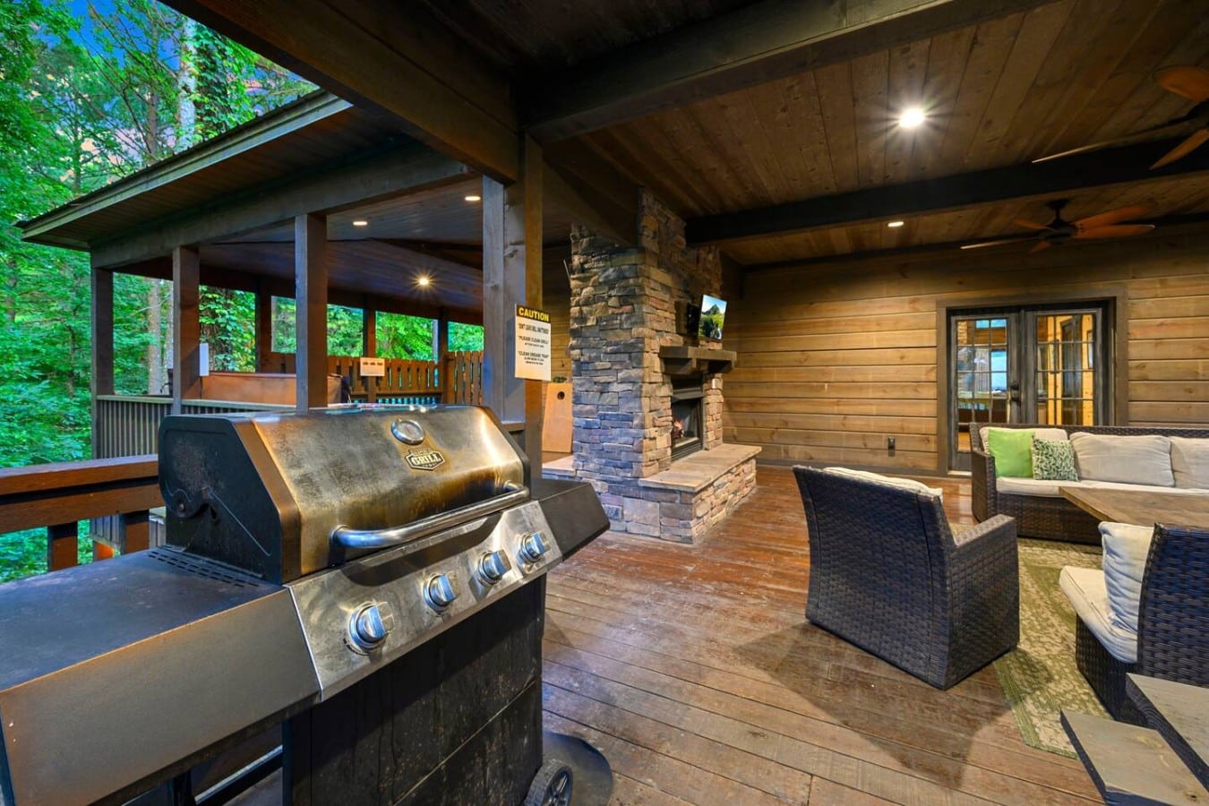 Covered deck with grill, fireplace, TV, and seating.