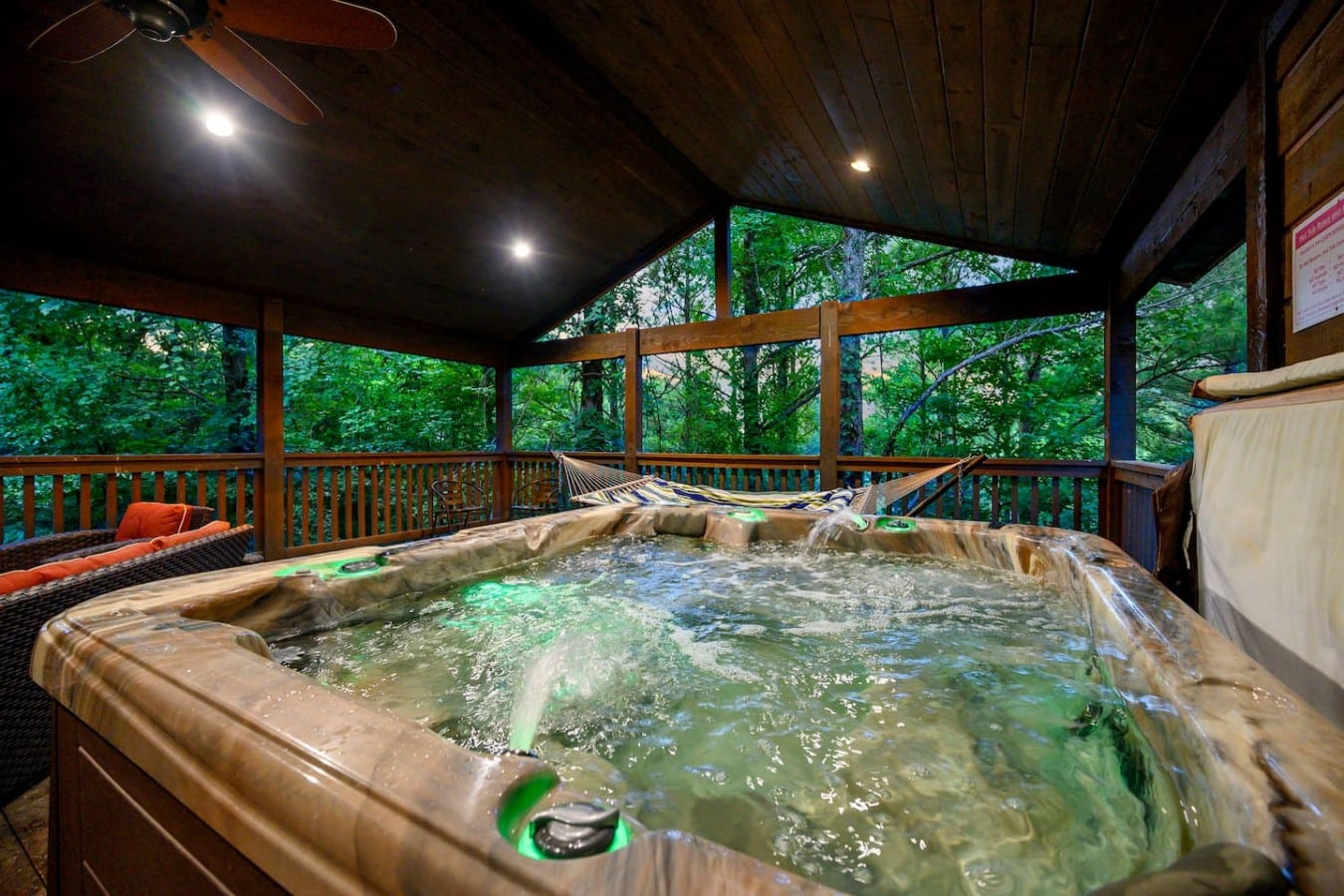 Covered hot tub with privacy and wooded views.
