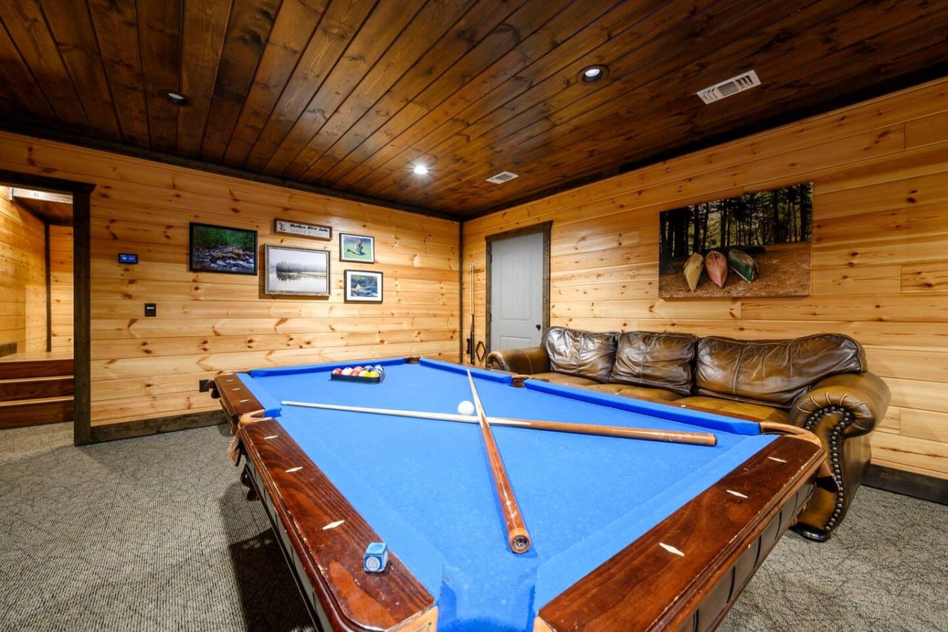 Pool table in the game room with sports decor and lounge seating.