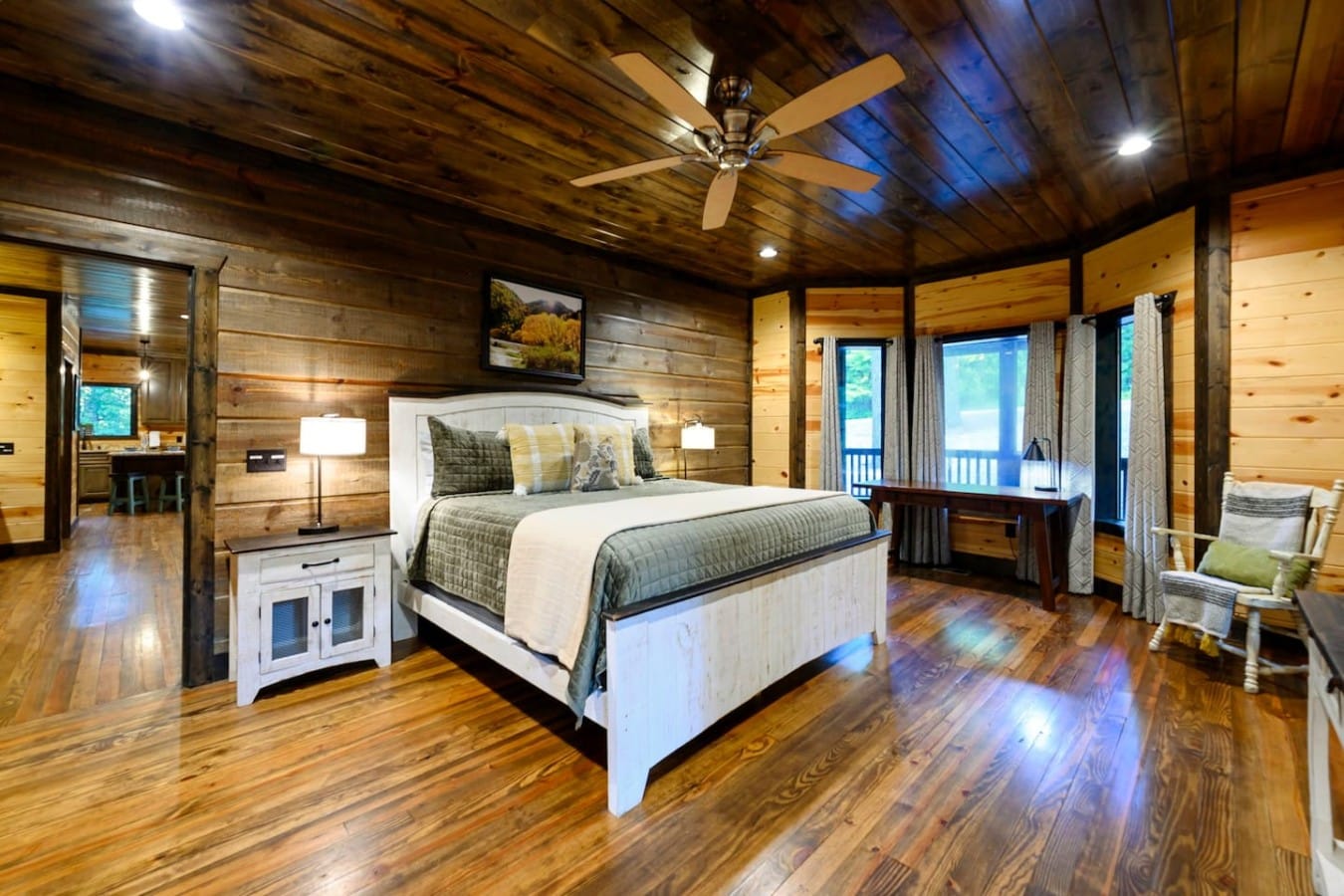 Primary bedroom with sitting area, TV, and warm wood ceilings.