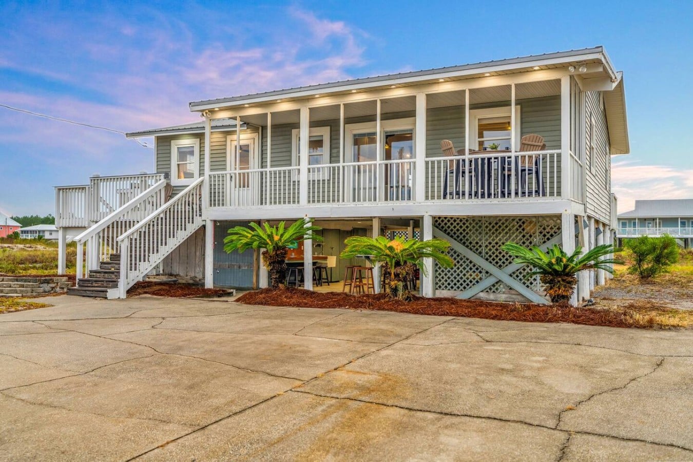 This stunning coastal retreat glows at twilight, offering porch living and bar seating galore.