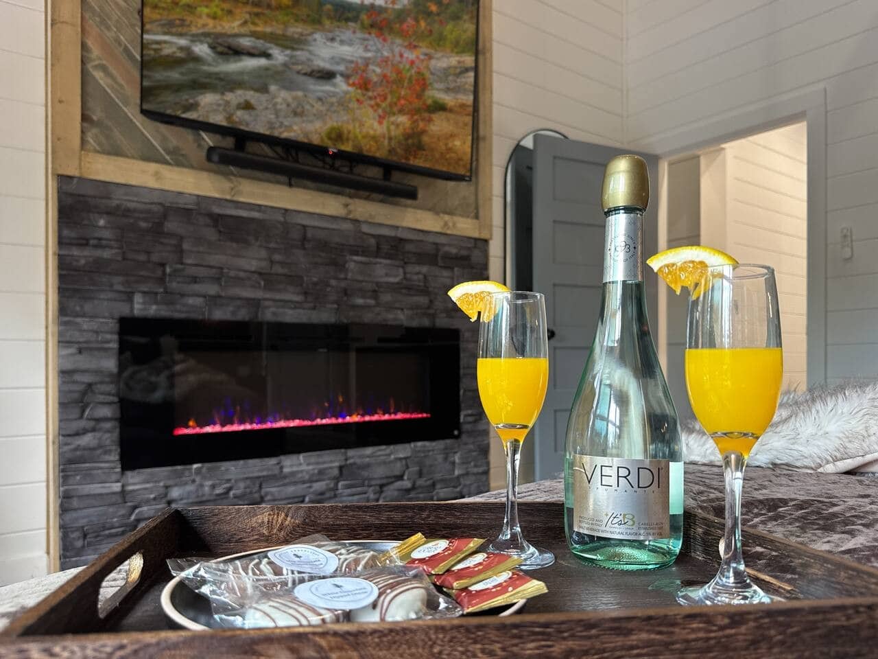 Sparkling wine, chocolates, and a glowing fireplace — the perfect welcome-night setup.