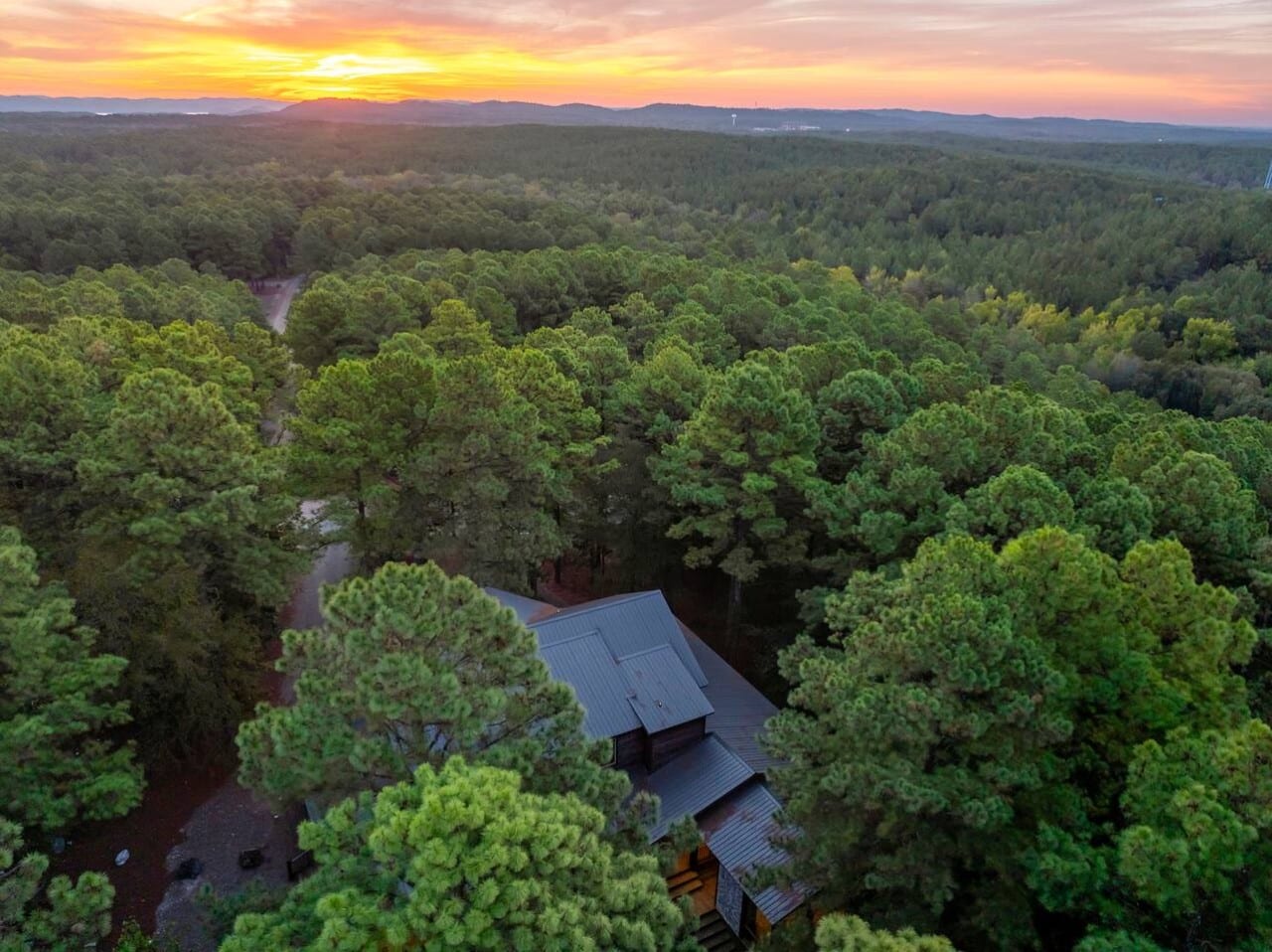 Mountains glow on the horizon as the sun sets over your treetop retreat.