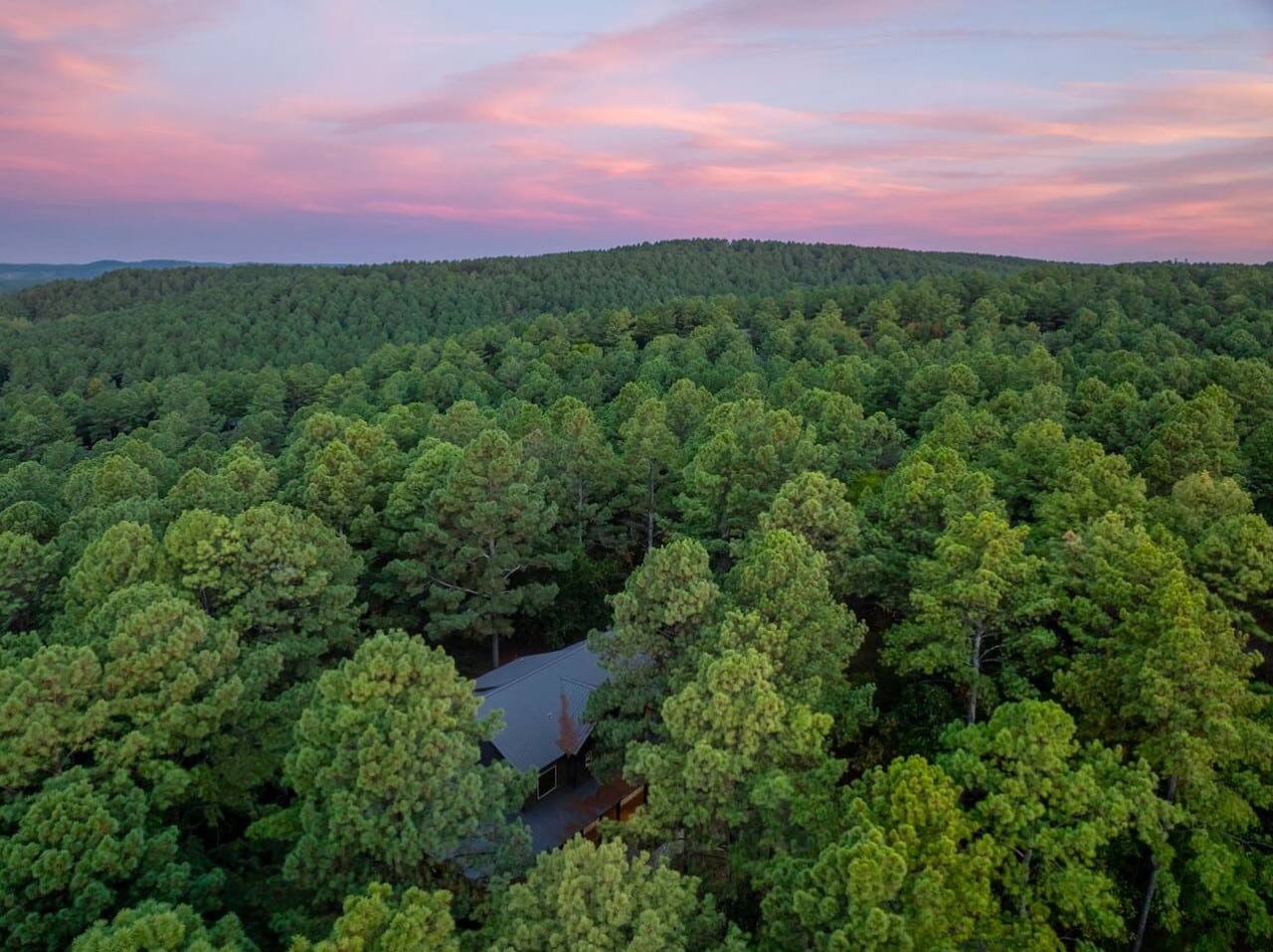 Your cabin disappears into a sea of pines under a breathtaking twilight sky.