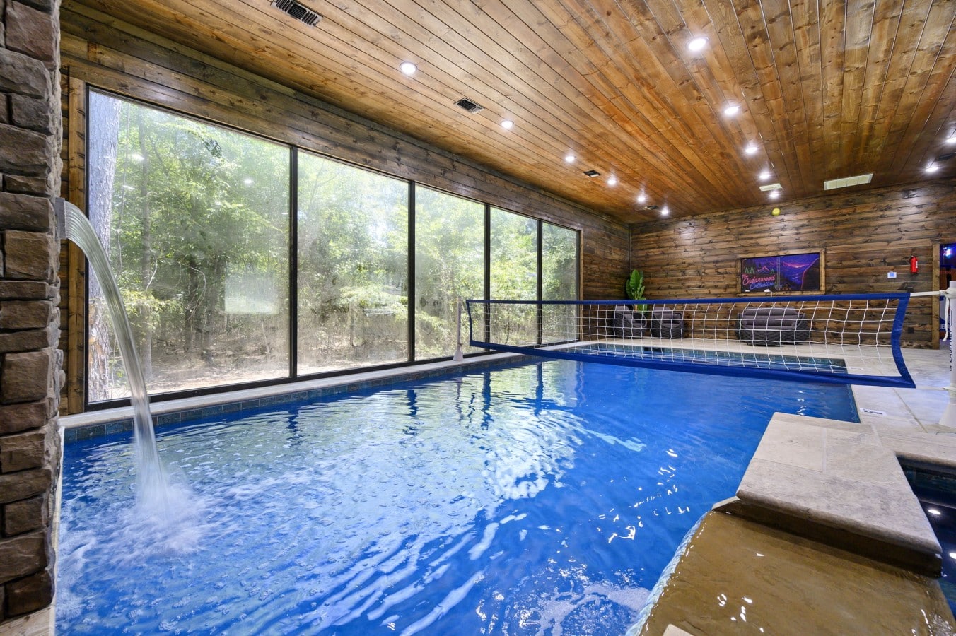 Splash, spike, and unwind in your private indoor pool with a stone waterfall and forest views.