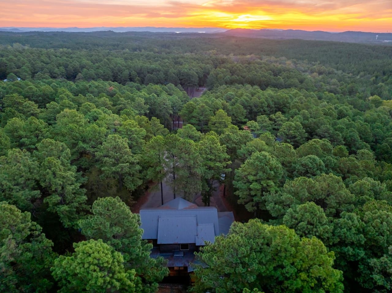 A fiery mountain sunset crowns your secluded pine forest hideaway at golden hour.