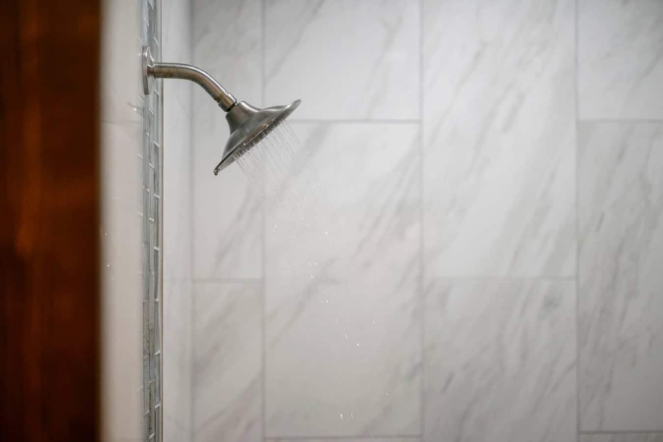 A rainfall showerhead and marble tile turn every rinse into a luxury experience.
