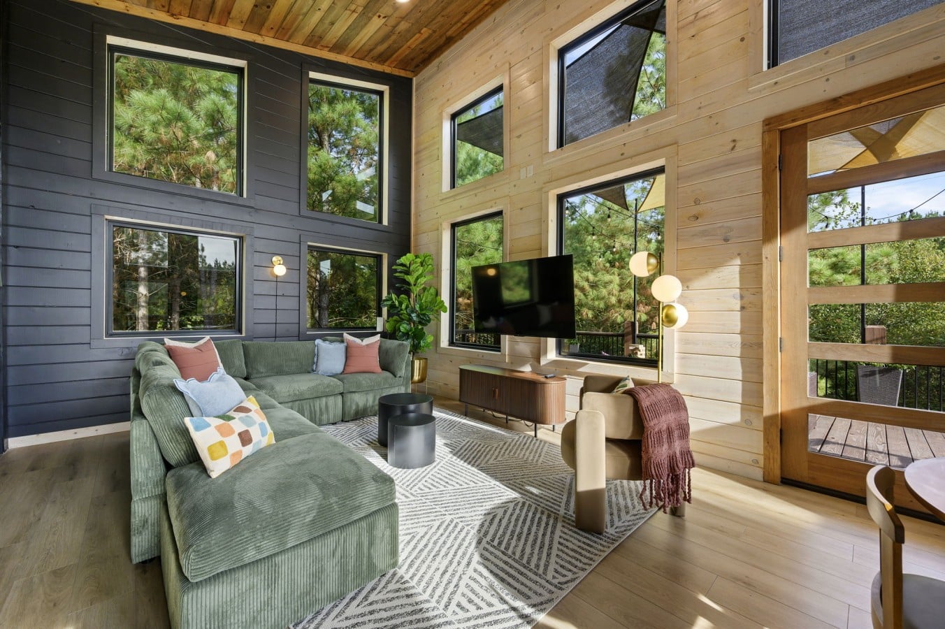 Two stories of windows and a green sectional — this living room is the gathering place.