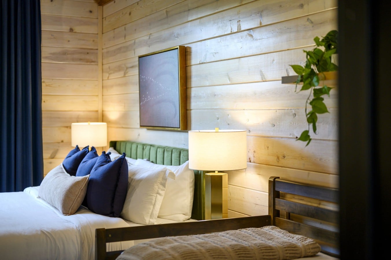 Soft brass light and trailing greenery create a nightstand nook worth lingering beside.