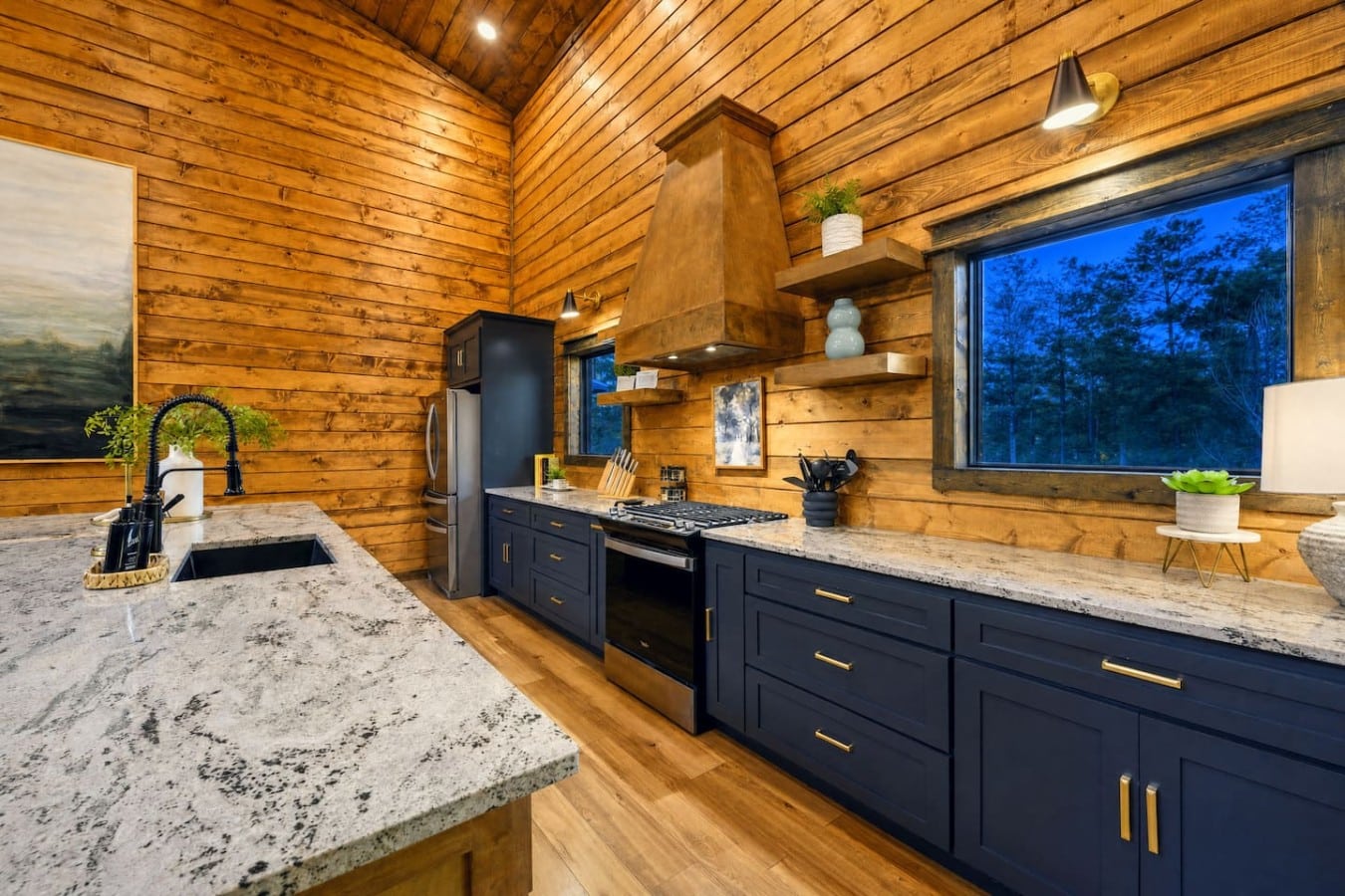 A gas range, copper hood, and forest views — cooking feels like luxury here.