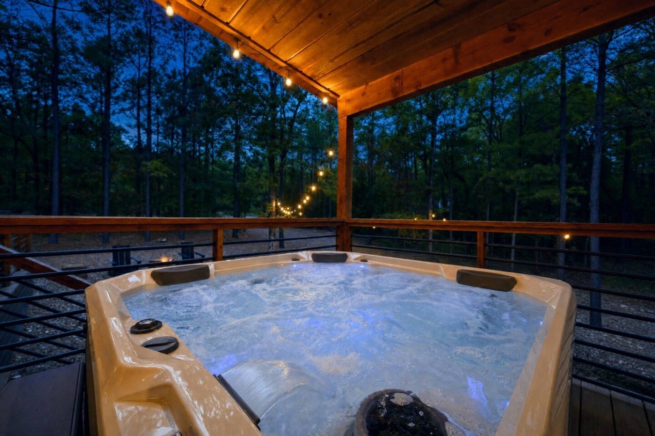 String lights shimmer overhead as steam rises from your private hot tub at twilight.