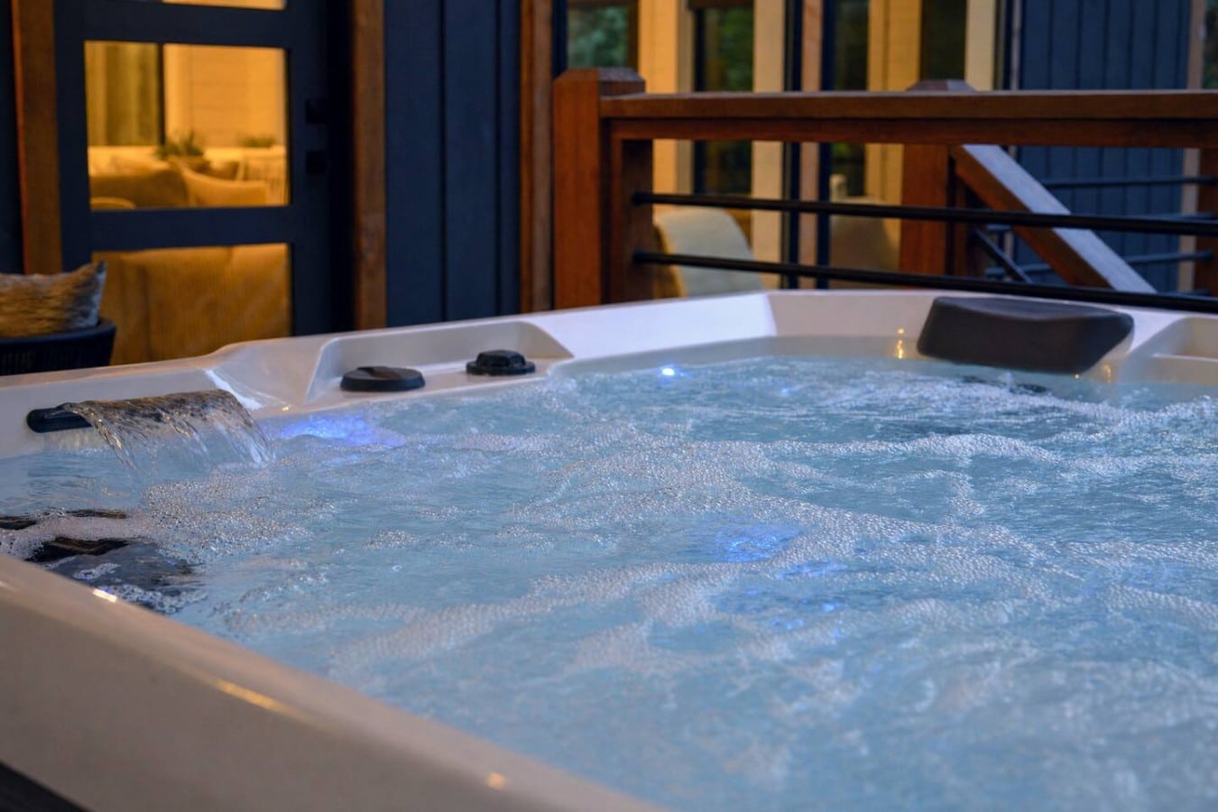 The waterfall hot tub glows blue at twilight—pure relaxation just steps from the living room.