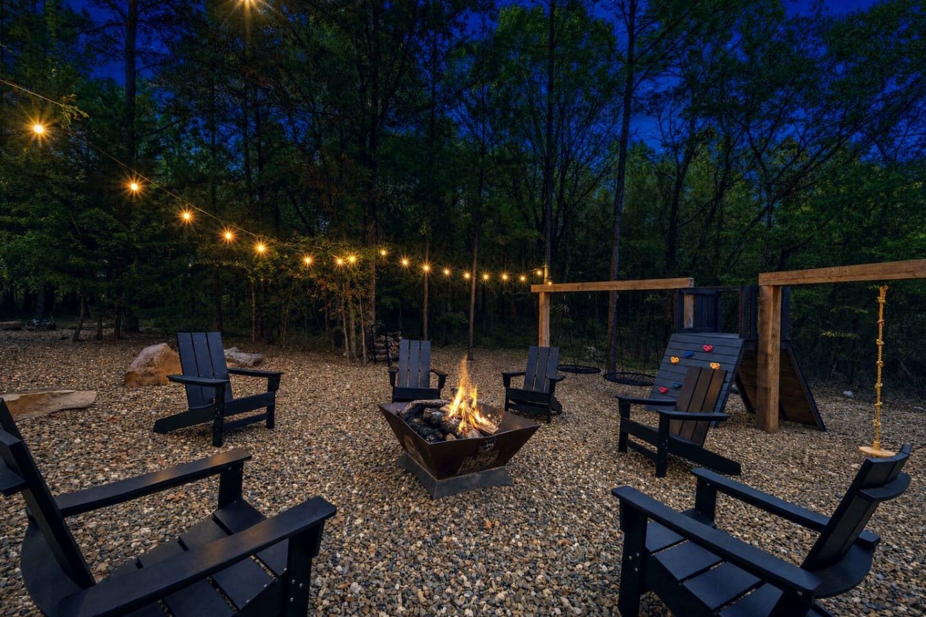 Kids play on the climbing wall while adults claim their chairs around the glowing fire pit.